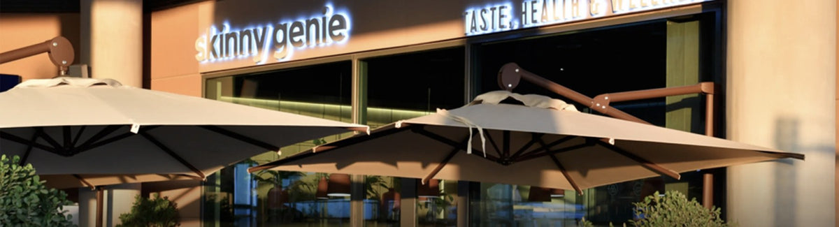 Skinny Genie café storefront at dusk with illuminated signage and outdoor seating